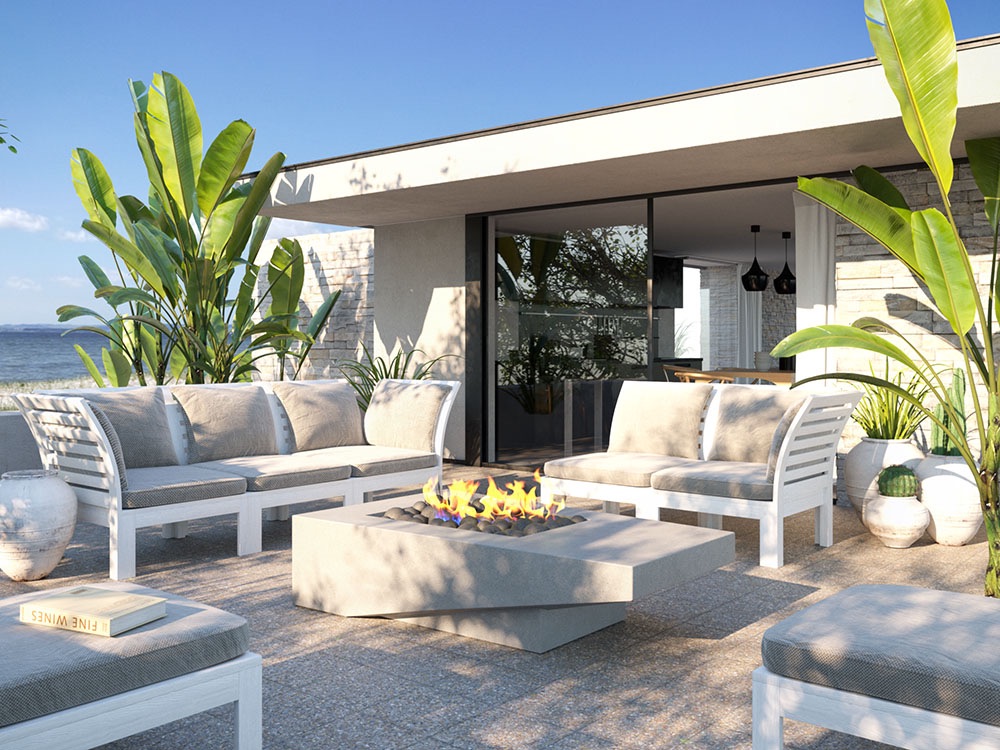 Low square Atlas concrete firepit with a flame among outdoor sofas on a seaside terrace